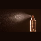 Brumelle Vanilla Coconut Scent Mist releasing a fine spray, close-up on a dark background